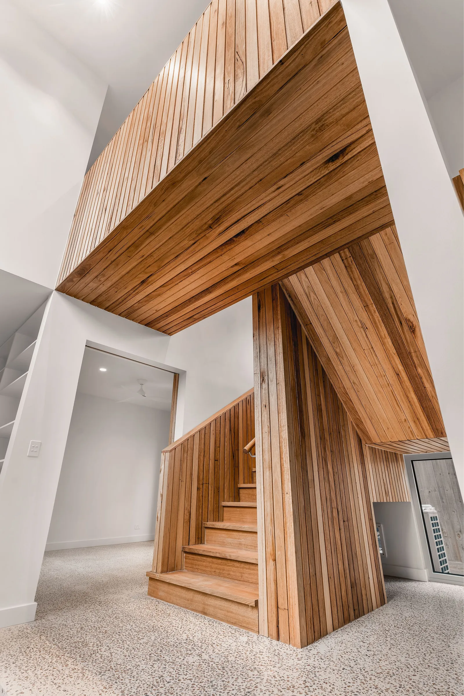 Dramatic timber-clad staircase with vertical slat cladding wrapping ceiling and walls
