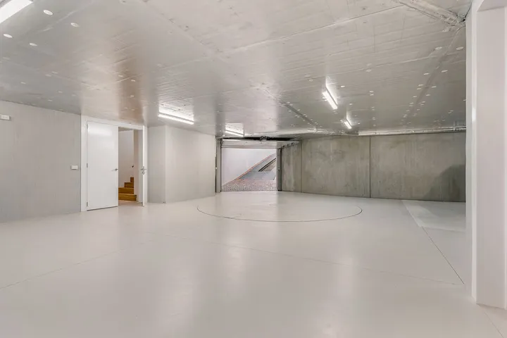 Spacious basement carpark with polished concrete floor, white walls and staircase access
