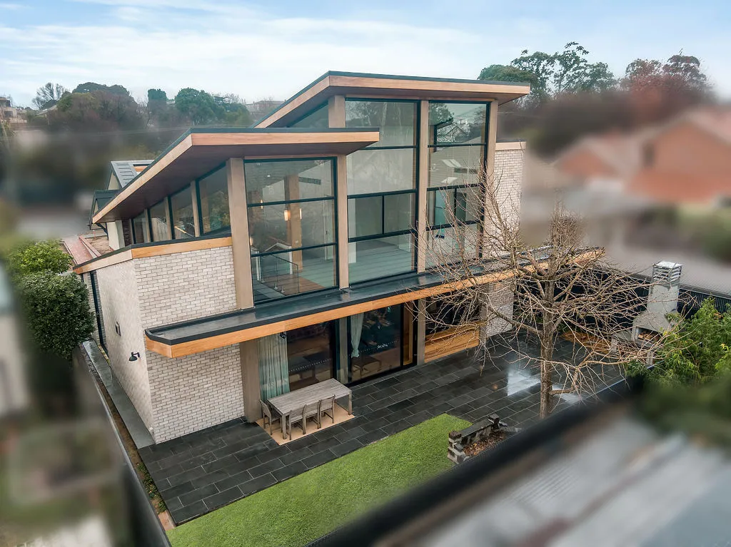 Aerial drone view of modern brick and timber home with expansive glazing and rear courtyard