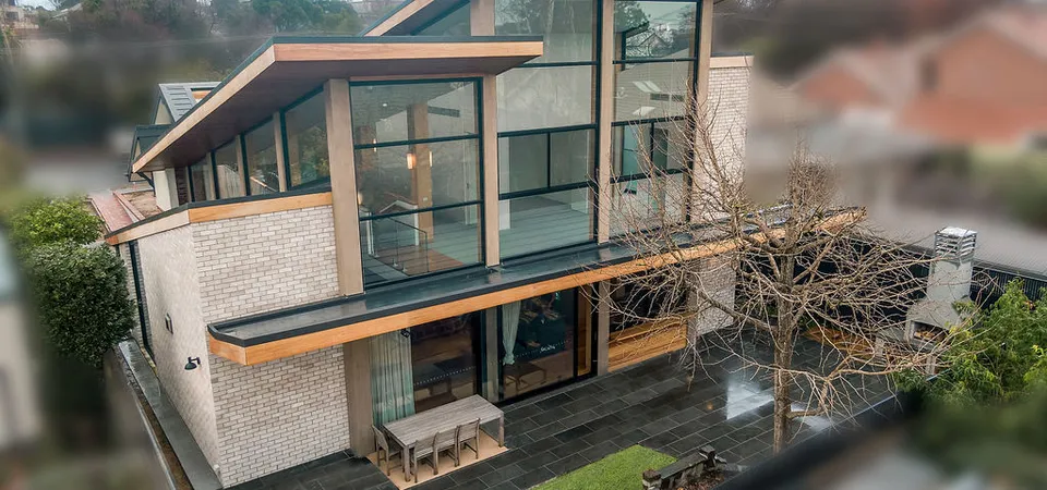 Aerial drone view of modern brick and timber home with expansive glazing and rear courtyard