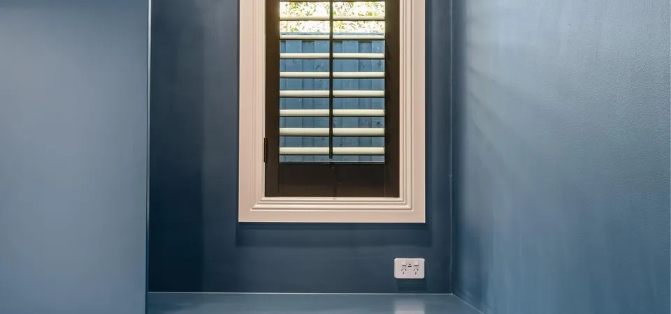 Blue nook with floating desk, plantation shutter window and timber floor