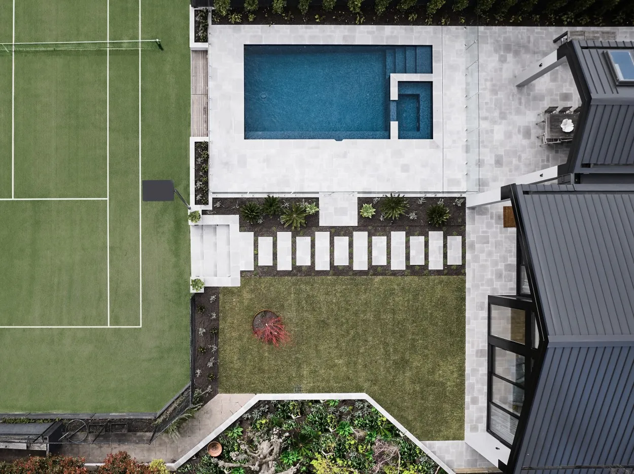 Aerial drone view of residential property with pool, tennis court, and landscaped garden