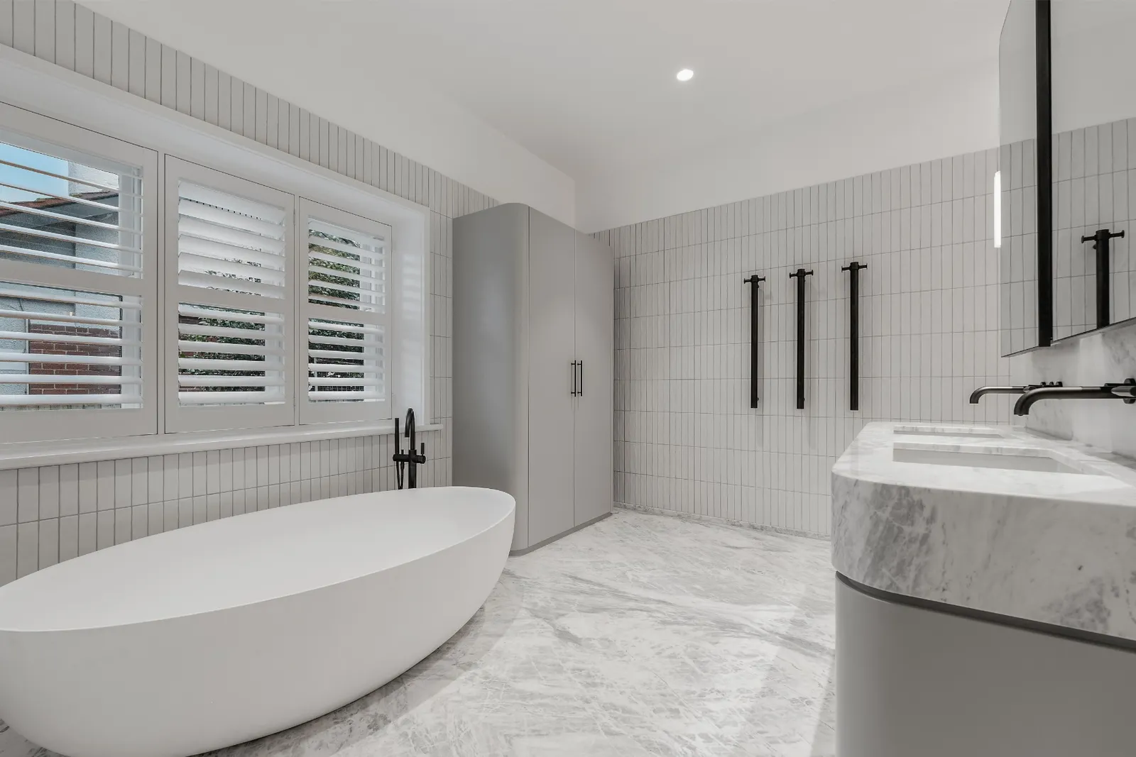 Bright ensuite bathroom with freestanding oval bath, white subway tiles and marble double vanity