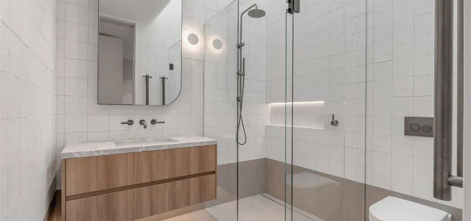 Bright white bathroom with freestanding oval bath, glass shower enclosure, and timber vanity