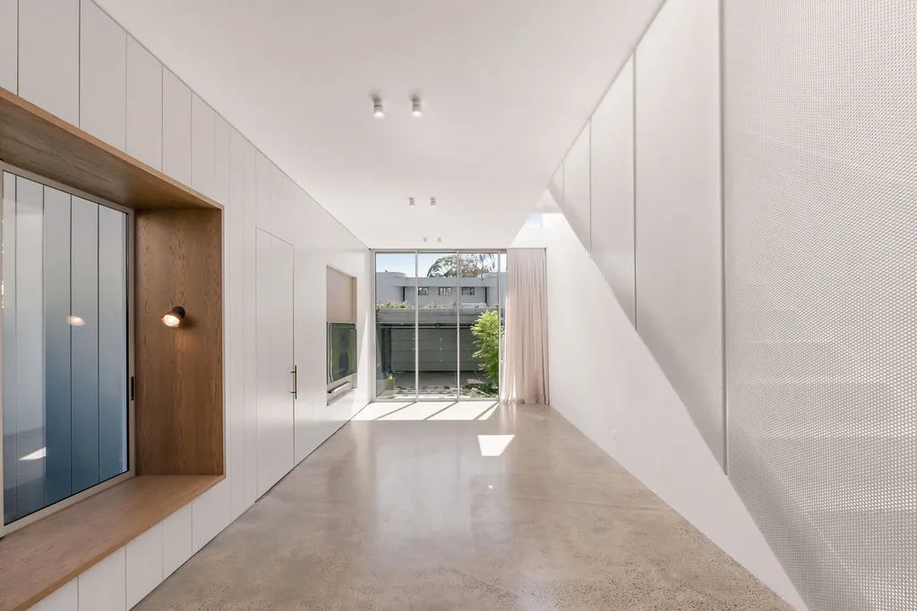 Bright minimalist hallway with polished concrete floor, full-height white joinery and courtyard view