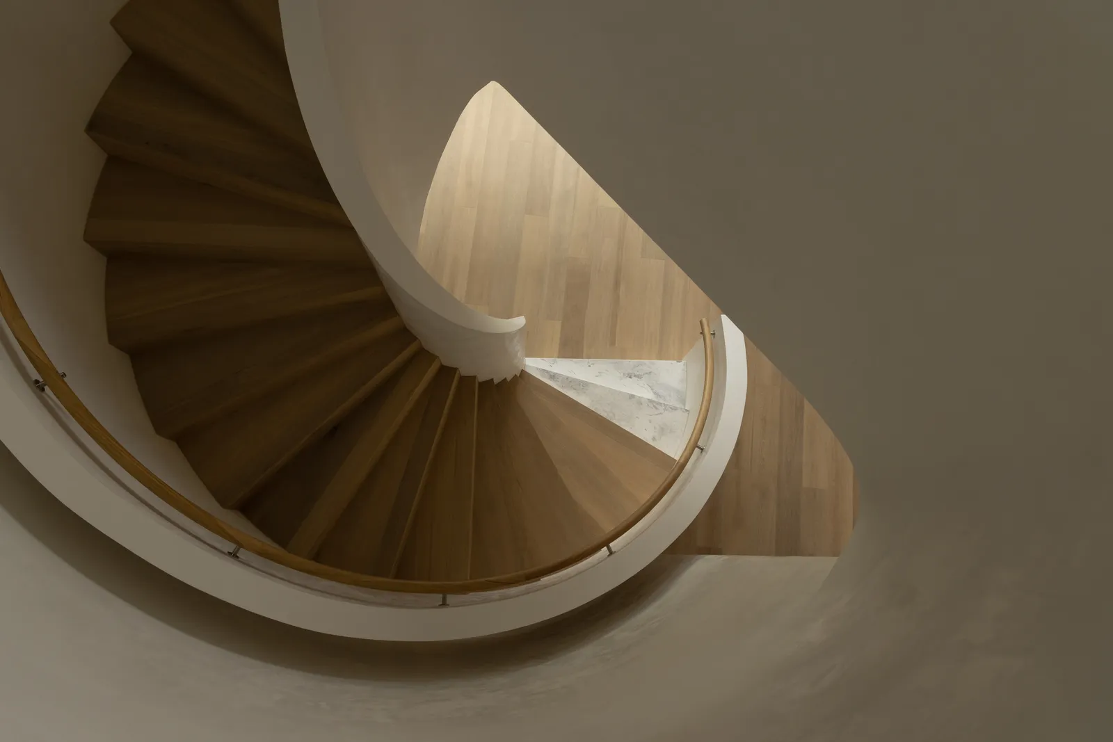 Aerial view of a sculptural timber spiral staircase with white curved balustrade