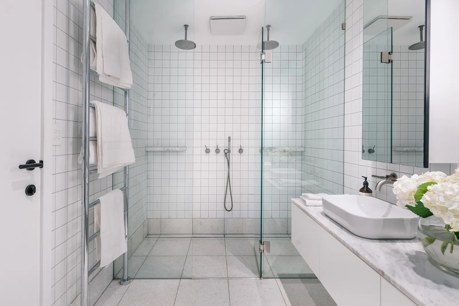 Bright white bathroom with dual rainhead shower and stone vanity