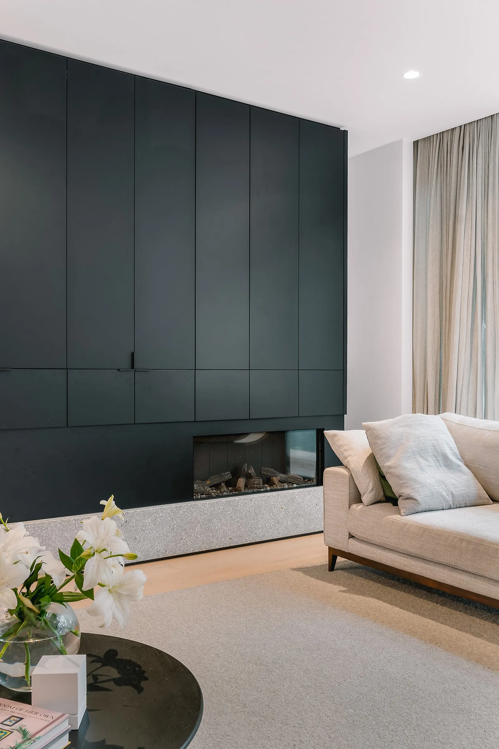 Dark joinery wall with integrated fireplace and soft seating