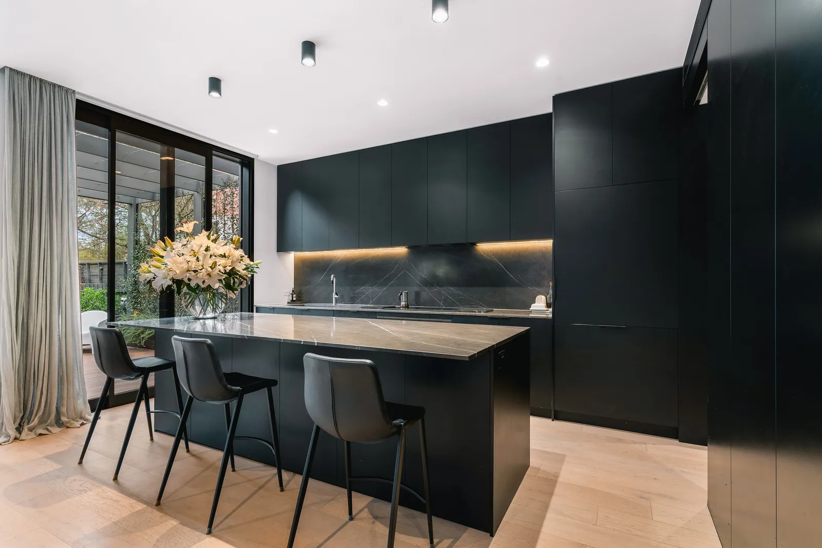 Matte black kitchen with marble island and bar stools