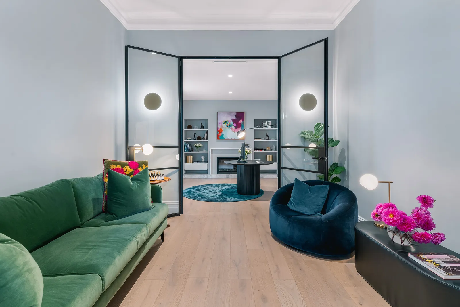 Green velvet sofa and navy armchair in a light filled living room
