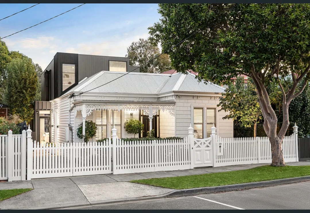 Victorian weatherboard facade with white picket fence, decorative verandah and dark upper-storey extension