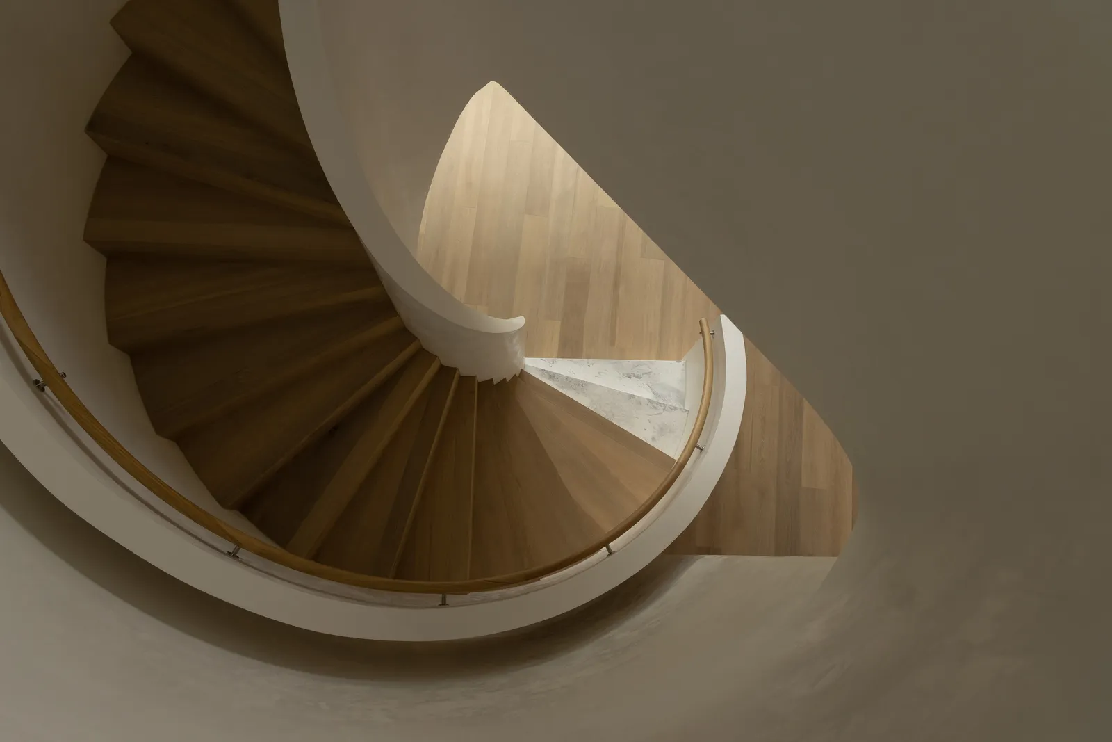 Aerial view of a sculptural timber spiral staircase with white curved balustrade