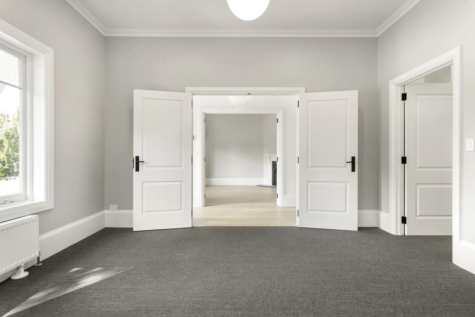Bedroom with double doors opening to the hallway, soft grey walls and new carpet