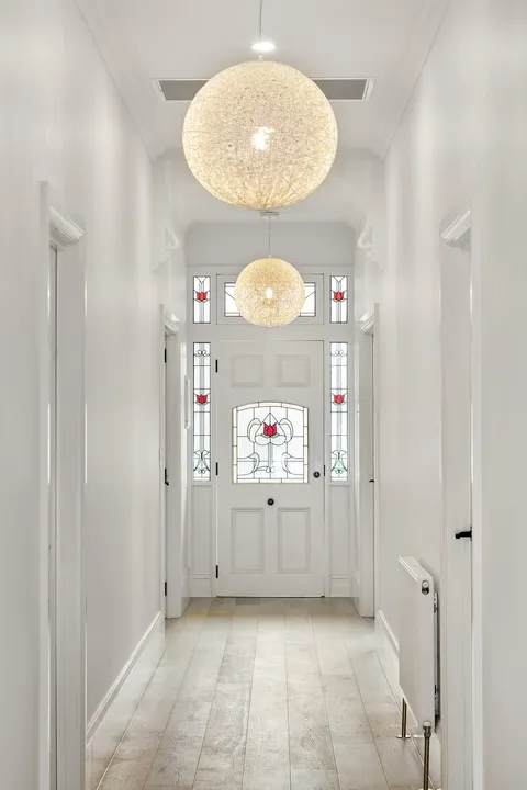 Entry hallway with original leadlight front door, white panelled walls and pendant lights