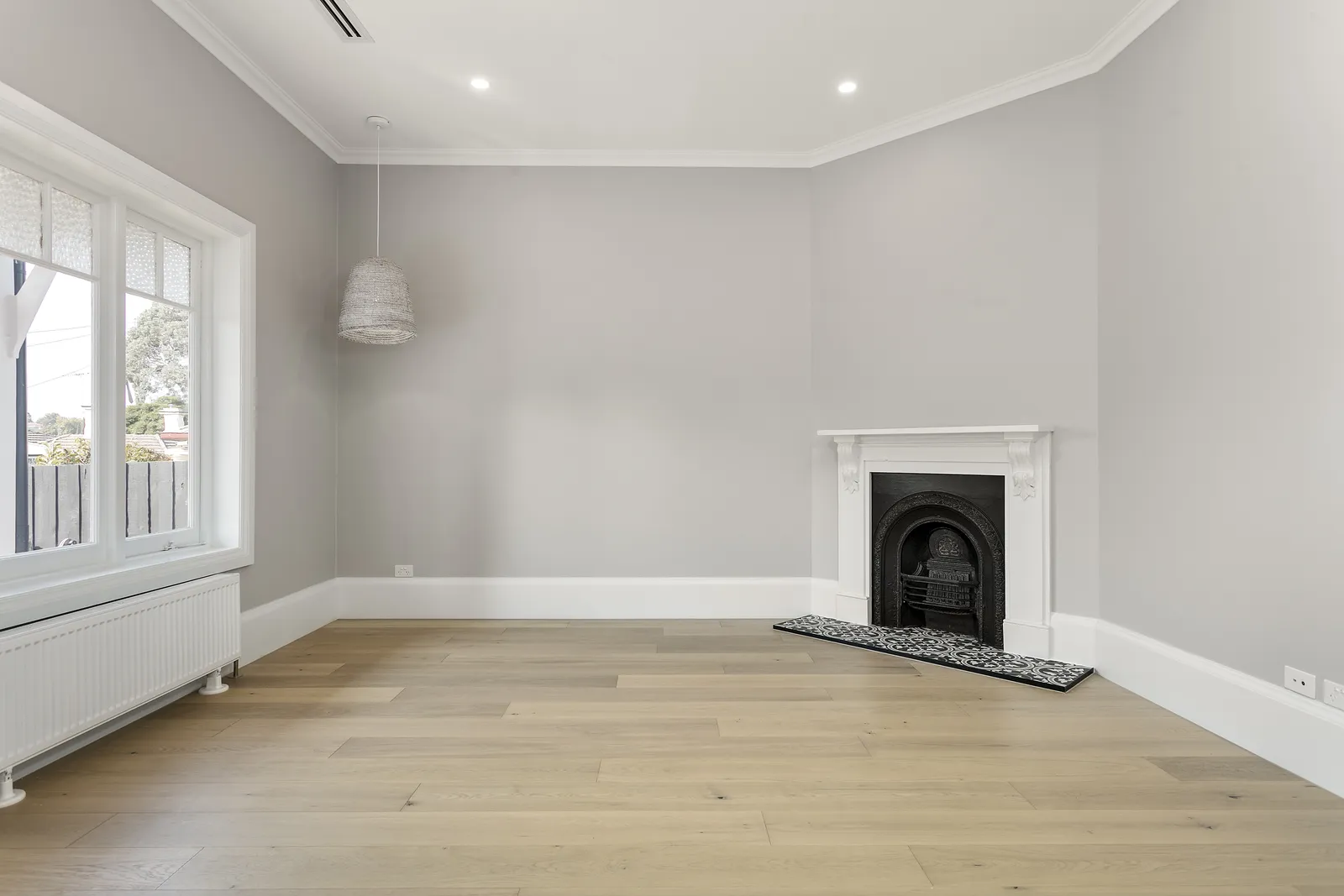 Restored front room with original open fireplace, white mantel and oak floors