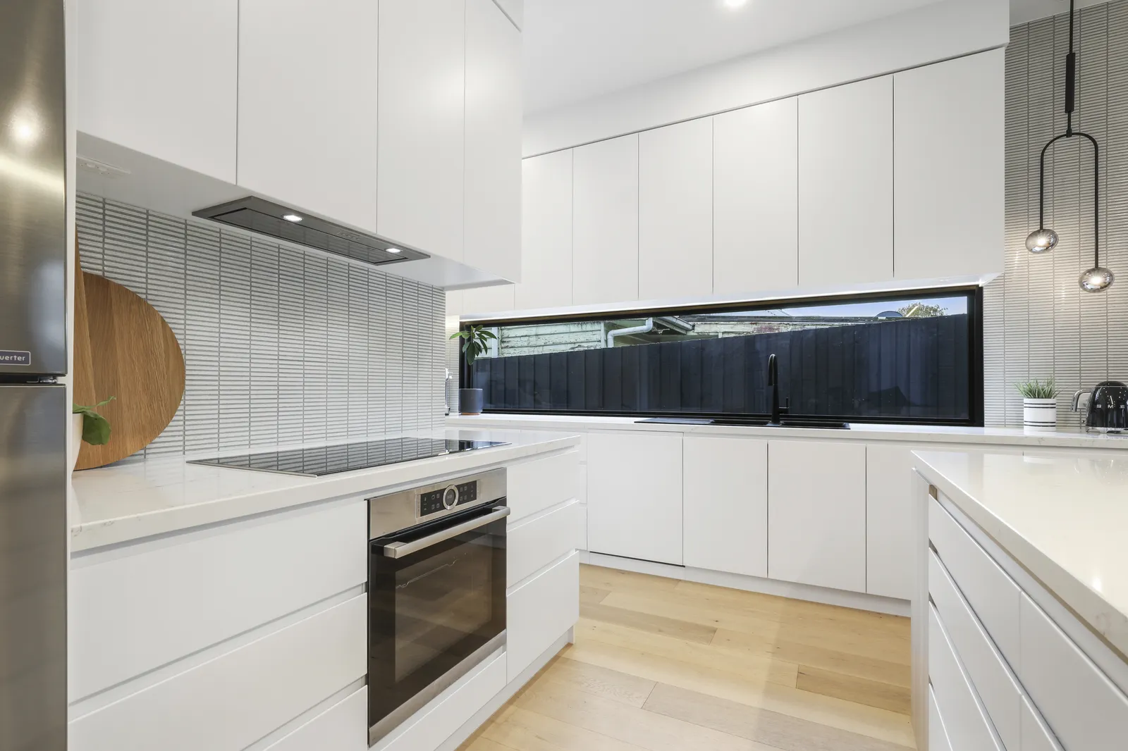 White kitchen with letterbox window splashback, integrated oven and stone benchtops