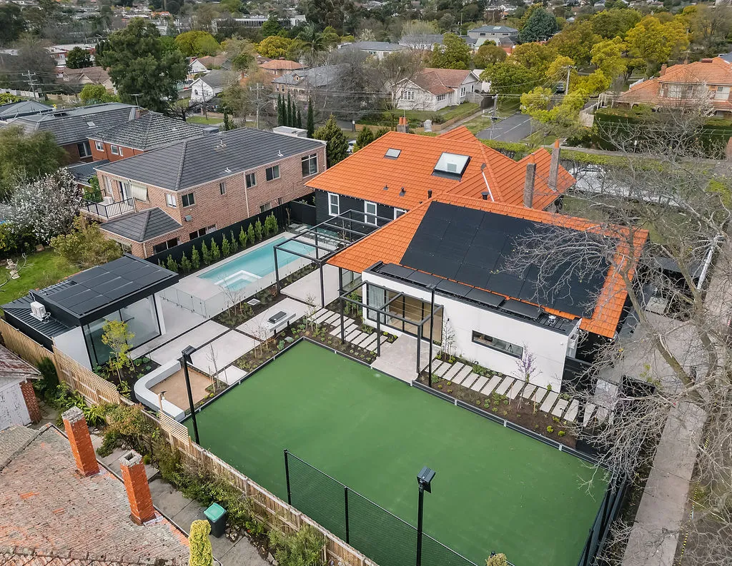 Aerial view of renovated home with terracotta roof, pool, spa, tennis court and lush gardens