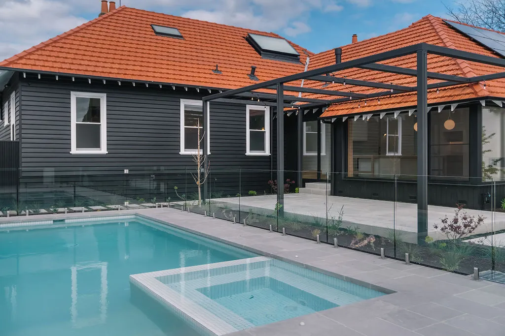 Rear exterior of renovated home with pool, spa, glass fencing, pergola and terracotta tile roof