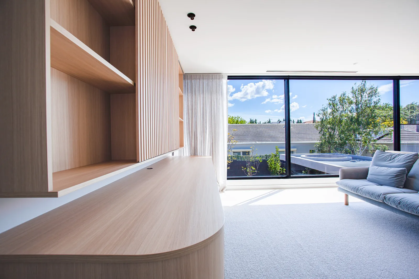 Timber study nook with slatted wall panelling, built-in shelving and floor-to-ceiling glazed outlook