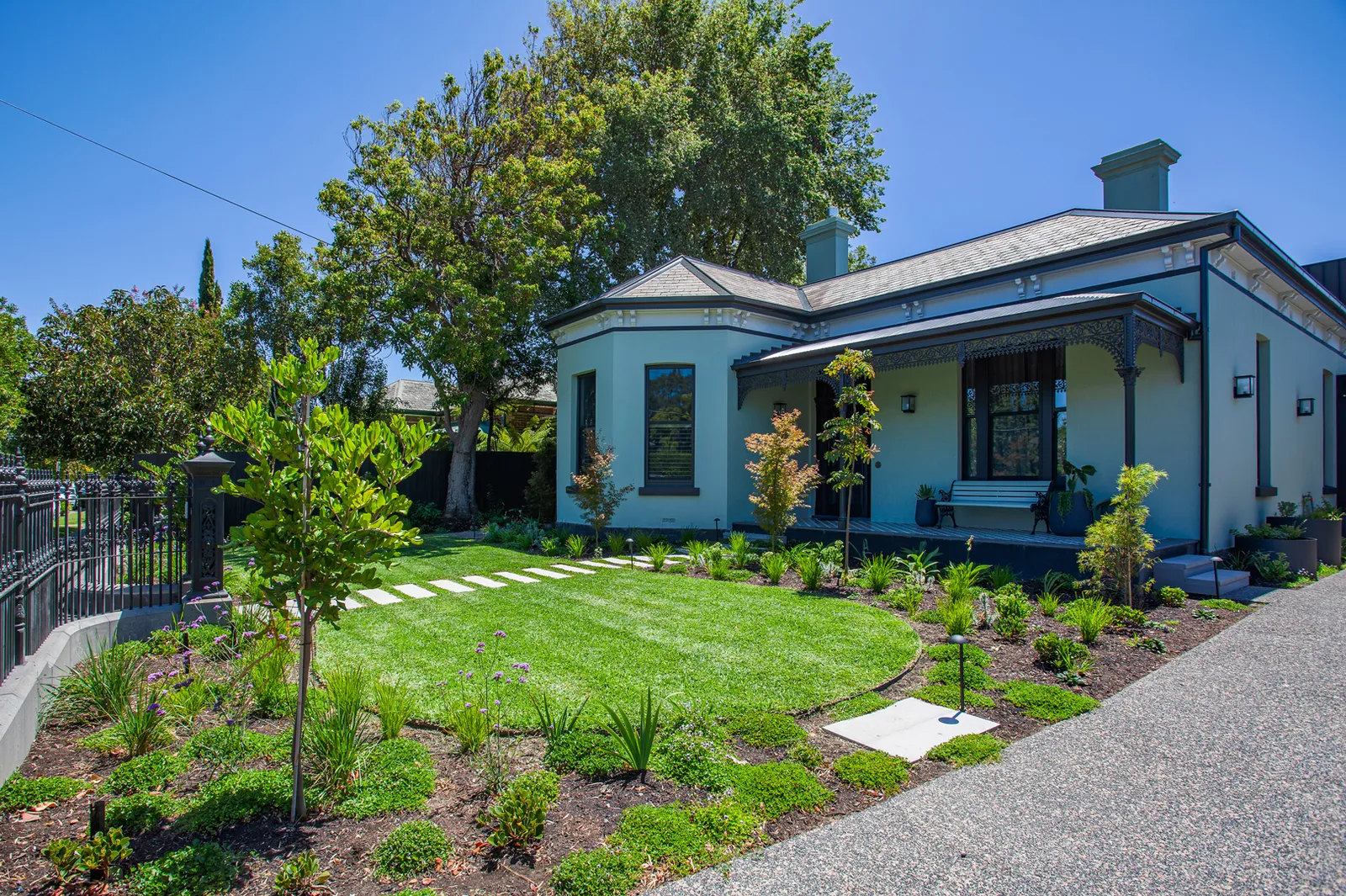Heritage pale green cottage with landscaped front garden, stepping stone path and wrought iron fence