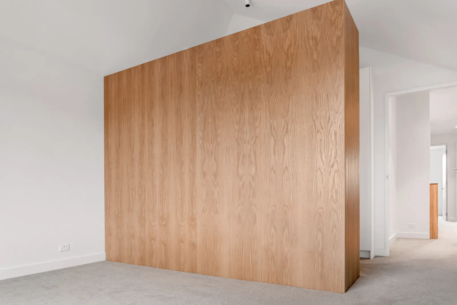 Floor-to-ceiling oak timber feature wall panel in open bedroom space