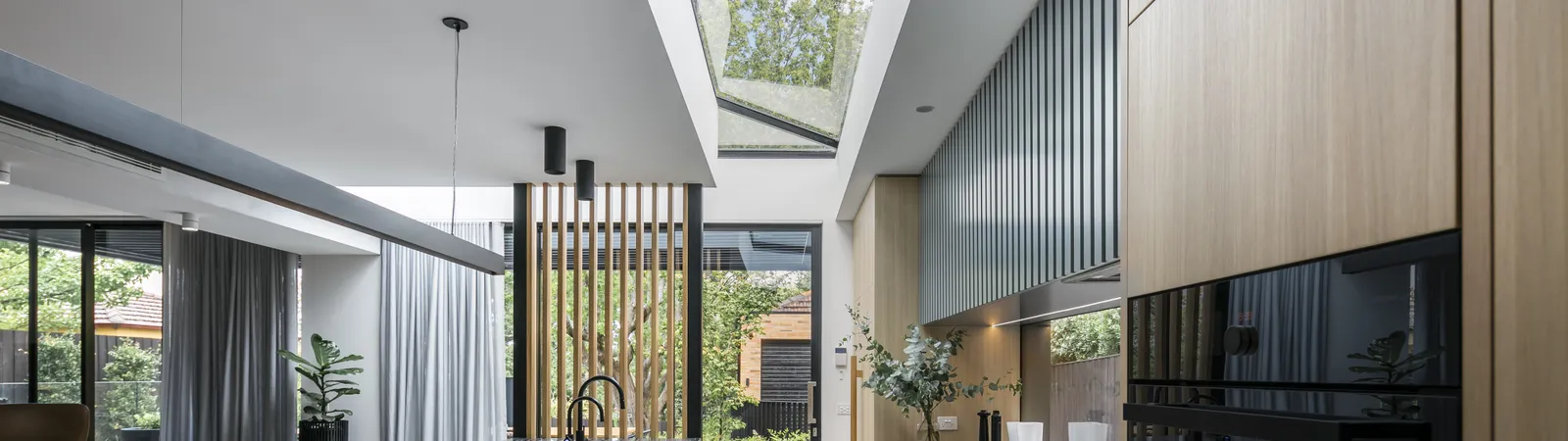 Open-plan kitchen with dark marble island, skylight, timber cabinetry, and garden views