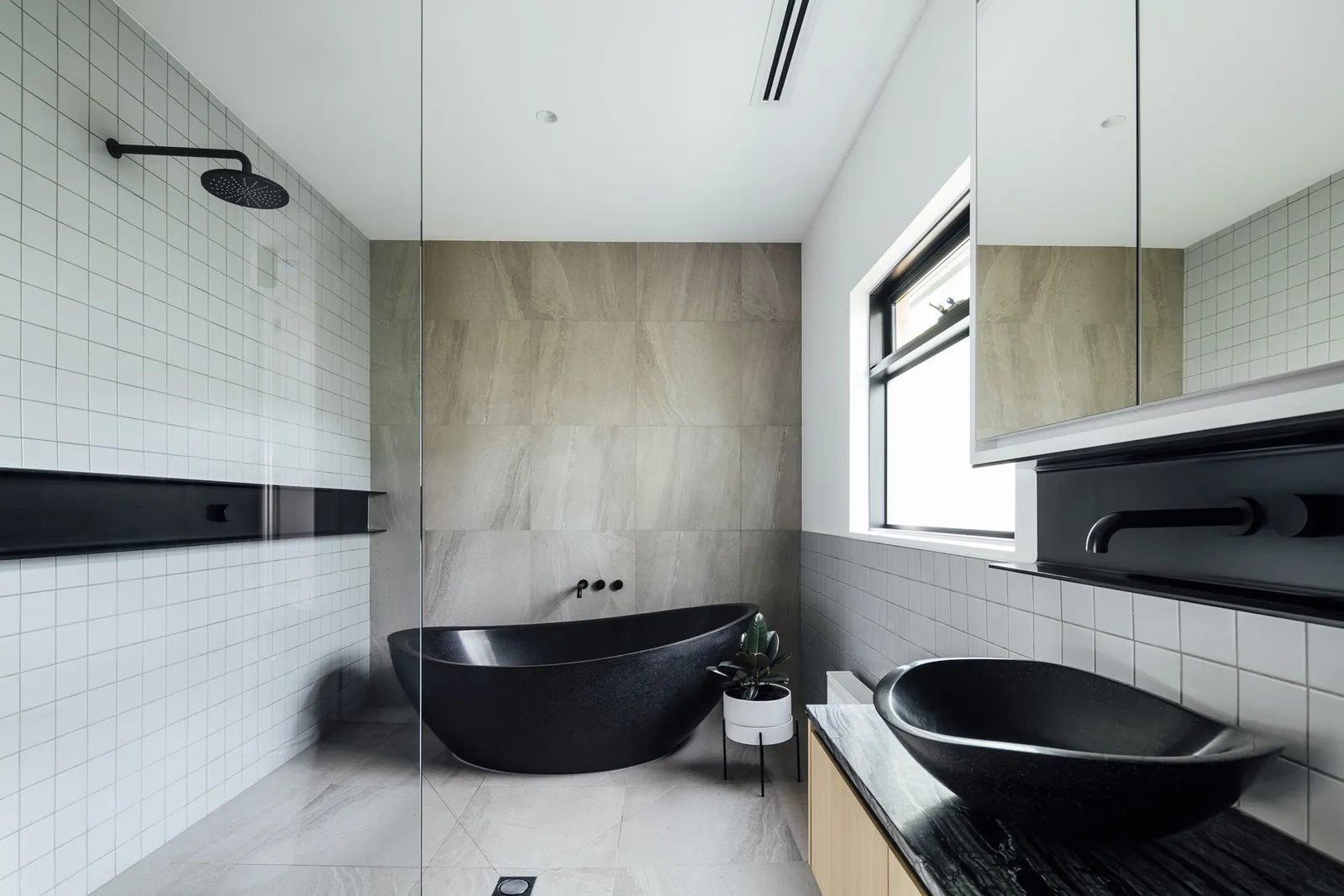 Modern ensuite with black freestanding bath, white grid tiles, marble feature wall, and black fixtures