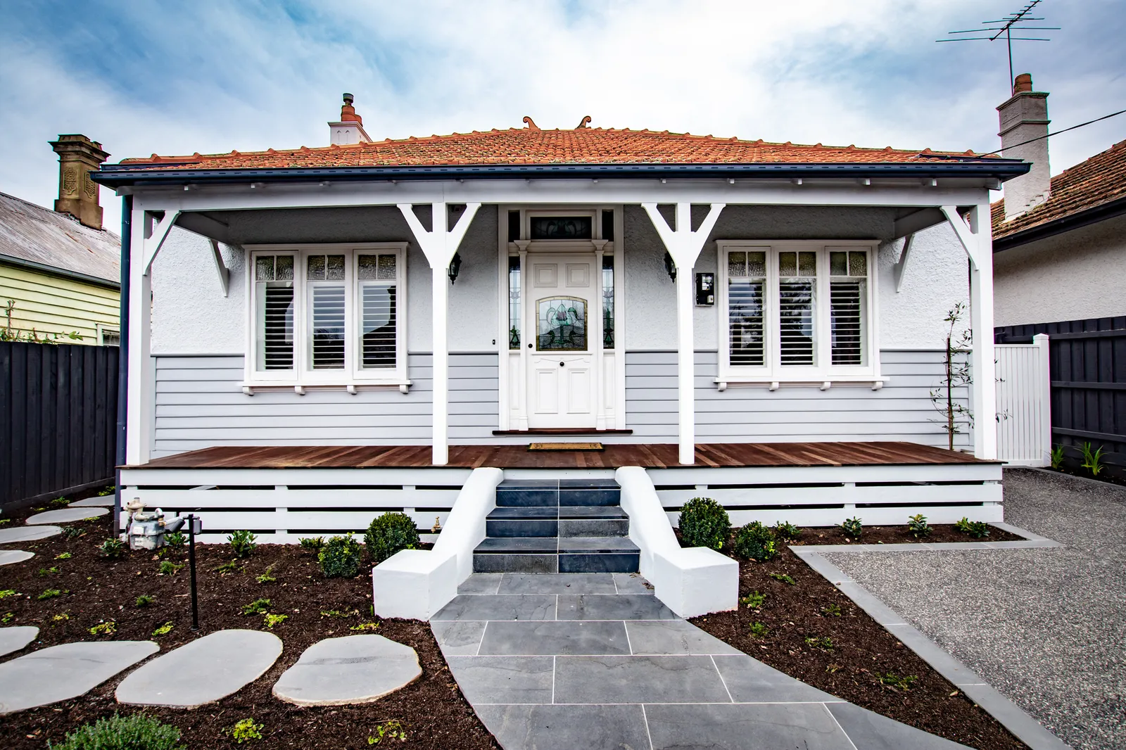 Renovated Edwardian weatherboard cottage facade with terracotta roof, verandah and slate pathway