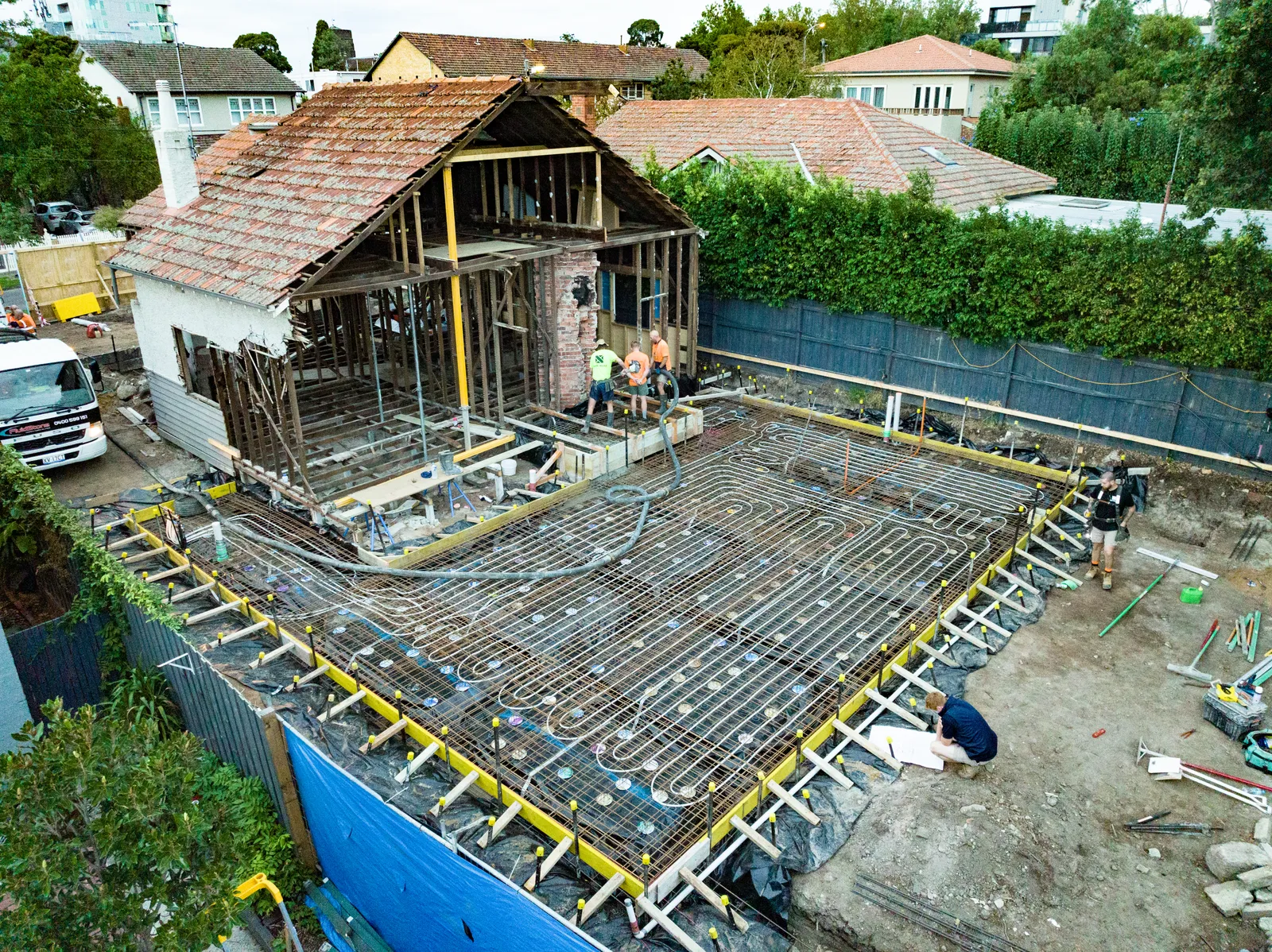 Aerial view of reinforced concrete slab with hydronic piping and partially demolished house