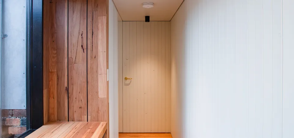 Narrow hallway with warm timber flooring, timber wall panelling and built-in bench seat