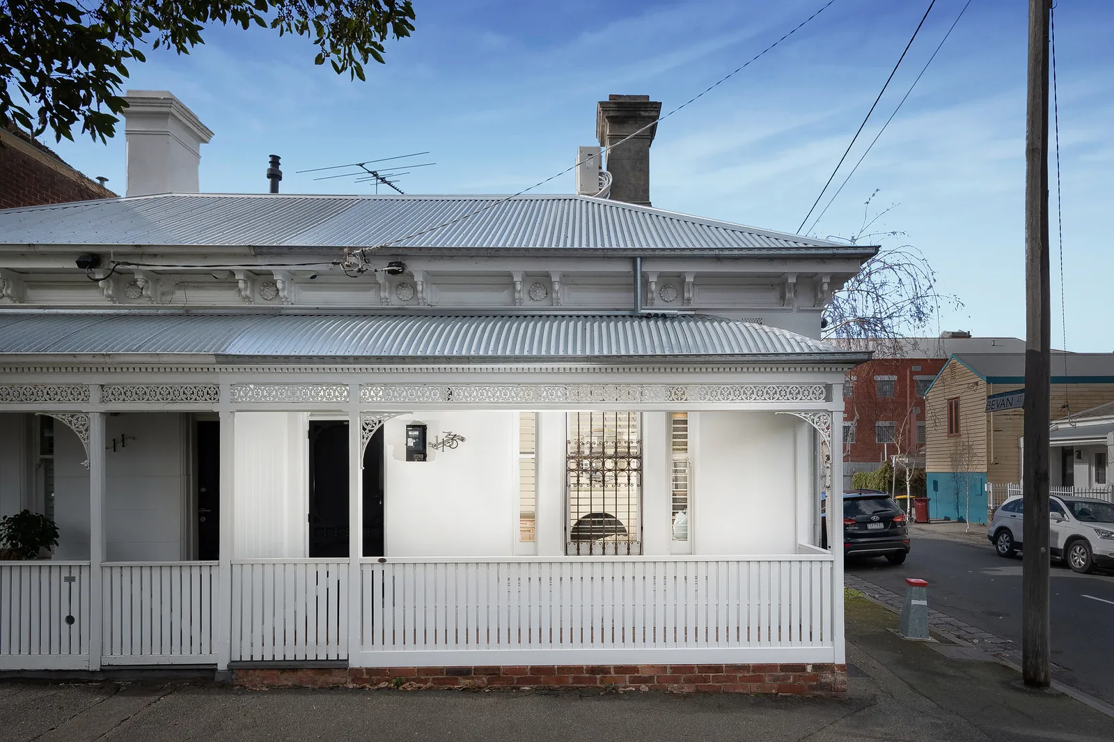 Victorian terrace street frontage with white painted facade, decorative iron lacework and verandah