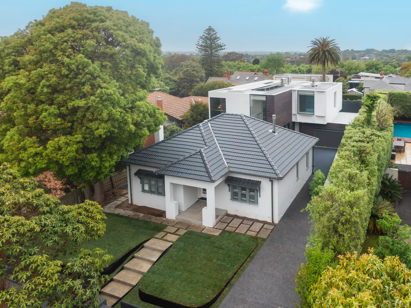 Aerial view of heritage bungalow with modern rear addition and lush garden surroundings in Kew