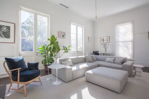 Light-filled living room with grey modular sofa, blue armchair, fiddle-leaf fig, and French doors