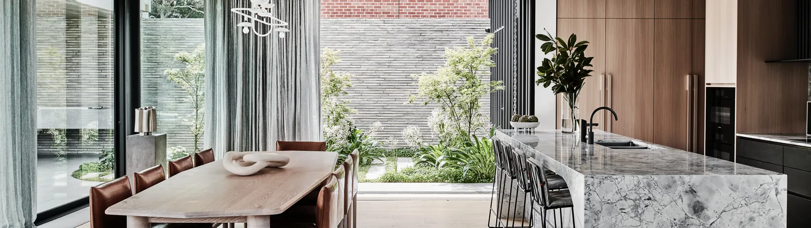 Open-plan kitchen and dining with marble island, timber cabinetry, and courtyard views