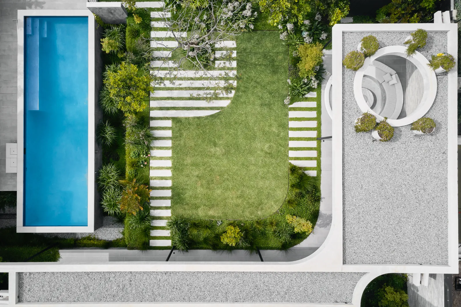 Aerial view of residential garden with rectangular pool, lawn, stepping stones and circular seating area