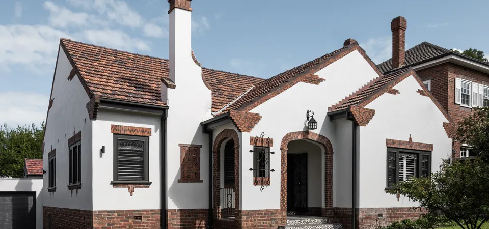 Full street-facing facade of art deco Camberwell home with tiled roof, brick detailing and arched entry