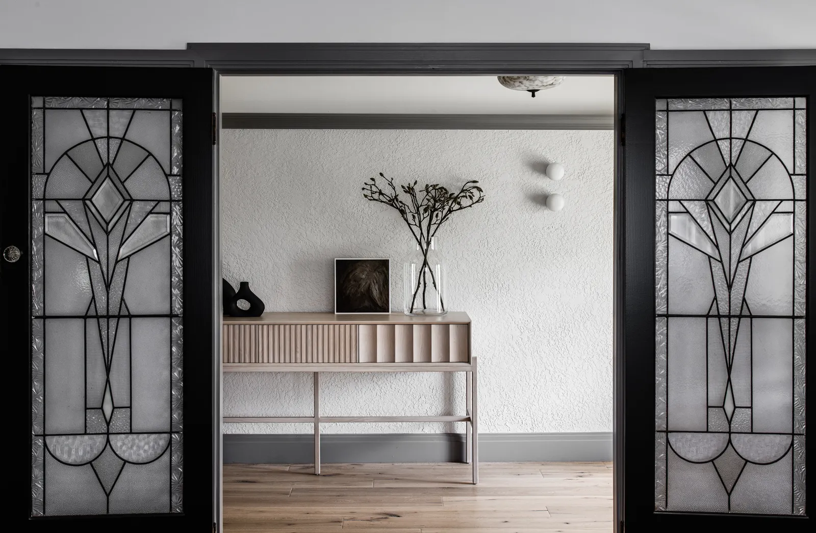Art deco stained glass double doors opening to console table with dried botanicals