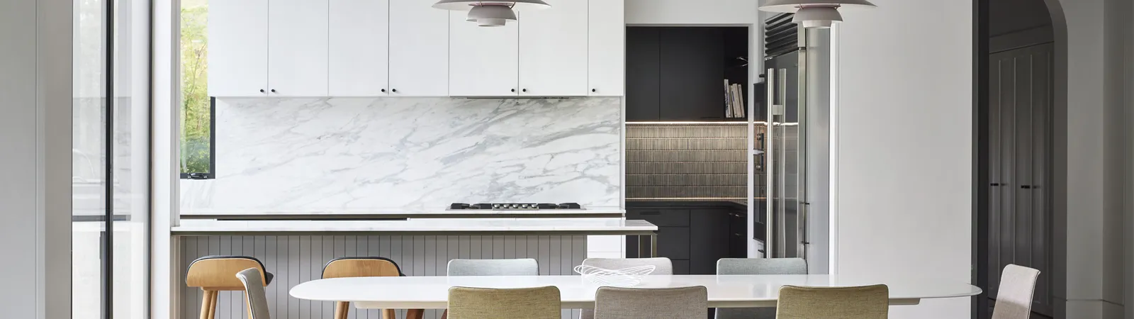 Bright open-plan kitchen and dining room with marble splashback and pendant lights