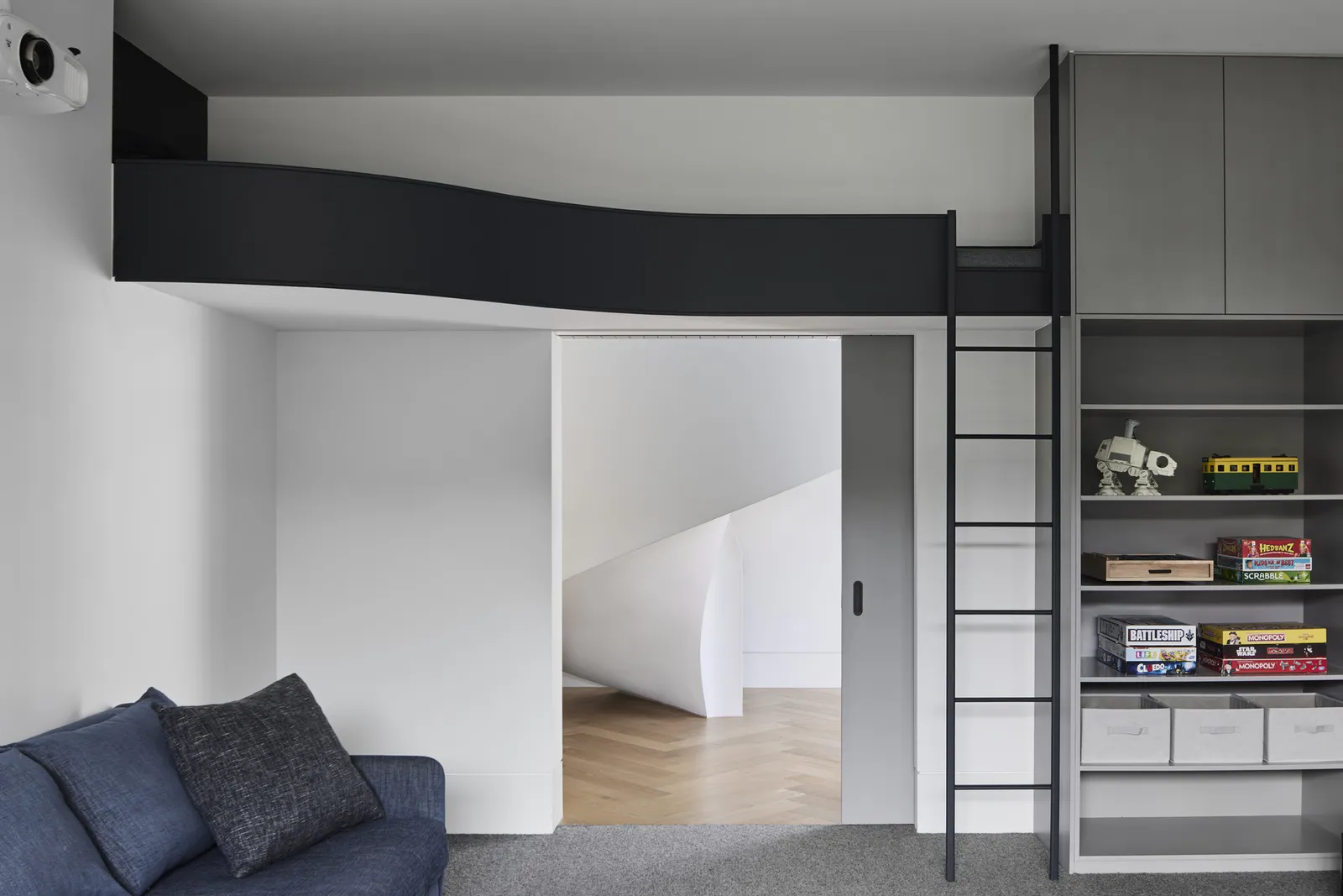 Contemporary kids' room with elevated loft platform, black metal ladder, built-in grey joinery and sofa